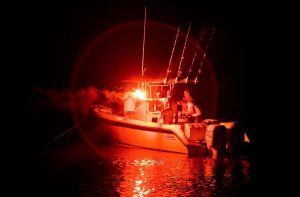 A boat at night on the water using a flare to signal distress.